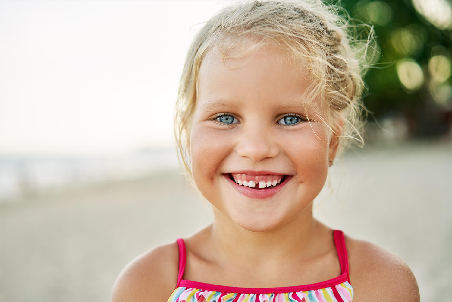 Lächelndes kleines Mädchen mit einer Zahnlücke am Strand
